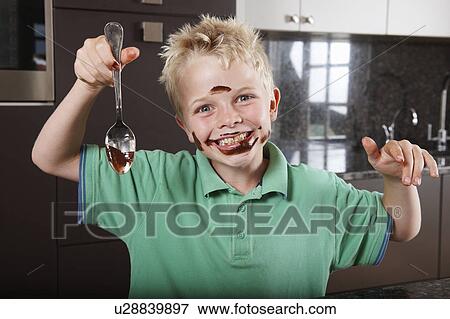 Stock Photo - Boy in kitchen with cake mix on his face. Fotosearch