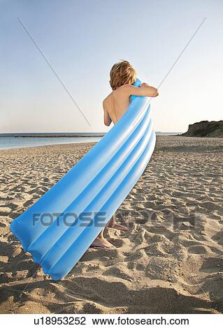 Stock Image - Boy inflating lilo on beach. Fotosearch