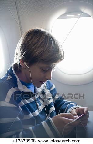 Boy listening to music on airplane View Large Photo Image Stock Photo - Boy listening to music on airplane. Fotosearch