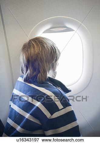 Stock Photo - Boy looking out of airplane window. Fotosearch