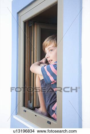 Picture - Boy looking out of window at view. Fotosearch