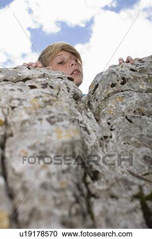 Stock Image - Boy looking over rocks. Fotosearch
