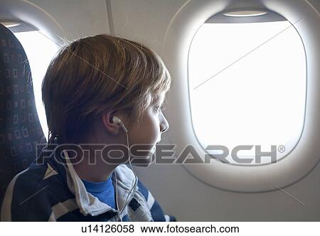 Stock Photo - Boy on airplane looking out of window. Fotosearch