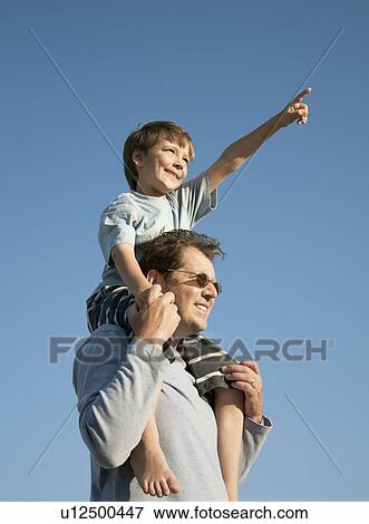 Boy on Dad's shoulders, looking at view View Large Photo Image Stock Photo - Boy on Dad's shoulders, looking at view. Fotosearch