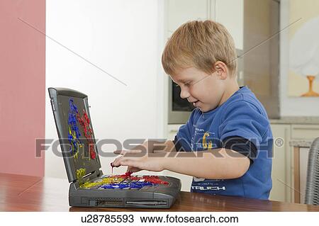Stock Image - Boy playing with paint on laptop. Fotosearch