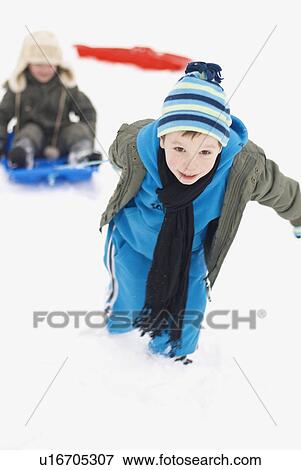 Boy pulling his friend on a sledge View Large Photo Image Stock Photo - Boy pulling his friend on a sledge. Fotosearch