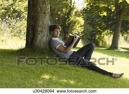 Picture - Boy reading a book in the park. Fotosearch