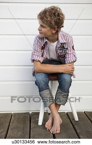 Boy sitting on chair View Large Photo Image Stock Photograph - Boy sitting on chair. Fotosearch