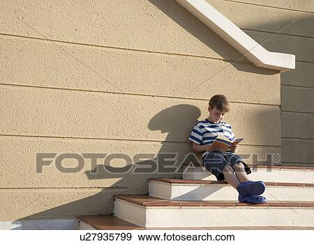 Stock Photo - Boy sitting reading book in sunshine. Fotosearch
