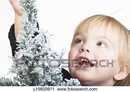 Stock Image - Boy standing by a snowy tree. Fotosearch