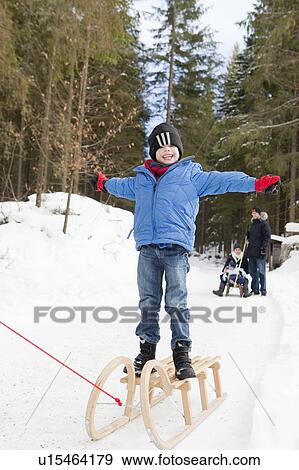 Boy standing on a snow sled View Large Photo Image Stock Photo - Boy standing on a snow sled. Fotosearch