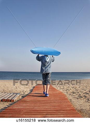 Boy walking down to the sea with lilo View Large Photo Image Stock Photo - Boy walking down to the sea with lilo. Fotosearch