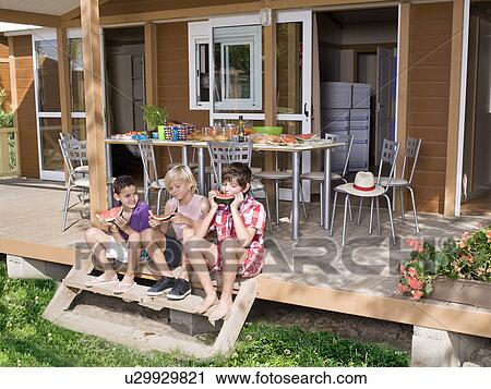 Boys eat watermelon sit on steps outside View Large Photo Image Stock Image - Boys eat watermelon sit on steps outside. Fotosearch