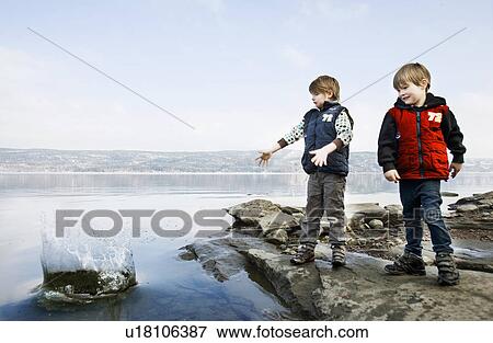 Boys playing with stones at lake View Large Photo Image Stock Photo - Boys playing with stones at lake. Fotosearch