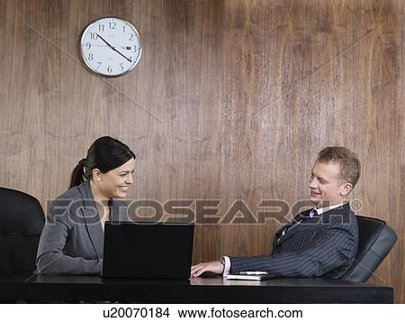 Picture - Business man and woman at desk. Fotosearch