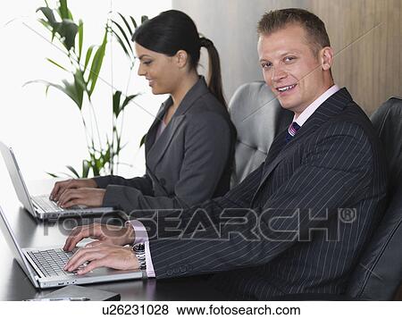 Stock Photo - Business man and woman at desk. Fotosearch