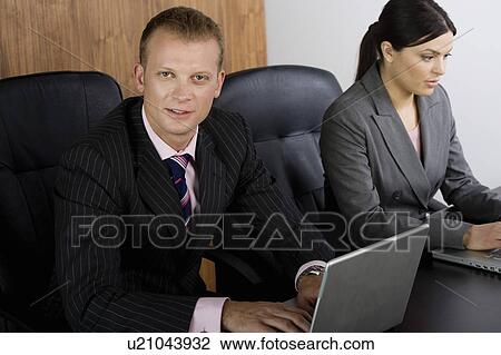Stock Image - Business man and woman on computers. Fotosearch