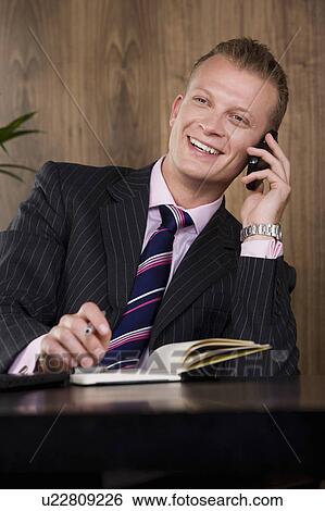 Stock Photograph - Business man at desk on phone. Fotosearch