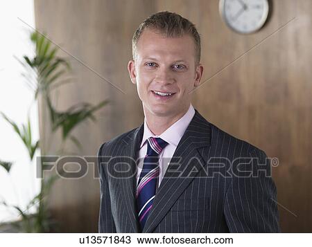 Stock Image - Business man smiling in his office. Fotosearch