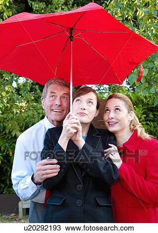 Stock Image - Business team shelter from rain. Fotosearch