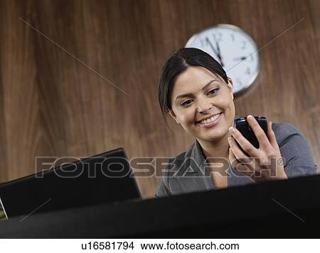 Picture - Business woman at desk with phone. Fotosearch