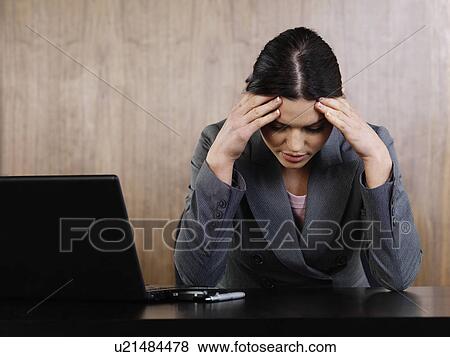 Stock Photo - Business woman head in hands in office. Fotosearch