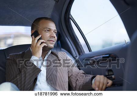 Stock Photograph - Businessman on the phone in limousine. Fotosearch