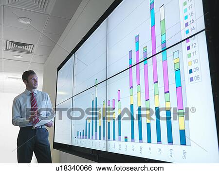 Stock Photograph - Businessman with graphs on screen. Fotosearch