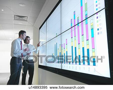 Stock Photography - Businessmen with graphs on screen. Fotosearch