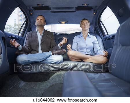 Stock Image - Businesspeople doing yoga in limousine. Fotosearch