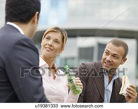 Stock Image - Businesspeople eating outdoors. Fotosearch