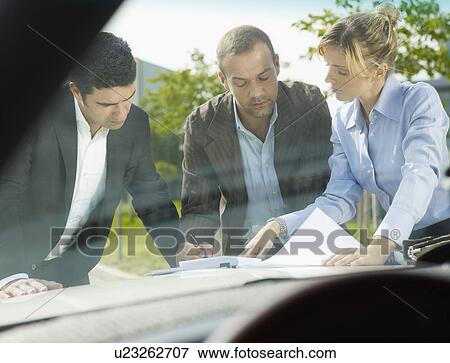 Businesspeople signing contract on car View Large Photo Image Stock Photo - Businesspeople signing contract on car. Fotosearch
