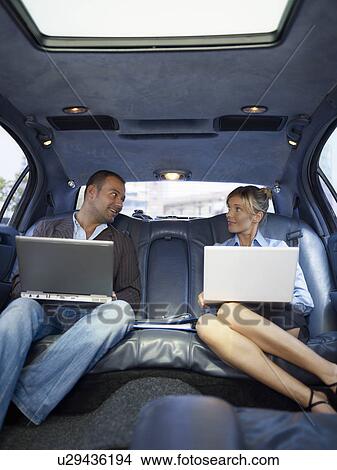 Picture - Businesspeople with laptop in limousine. Fotosearch