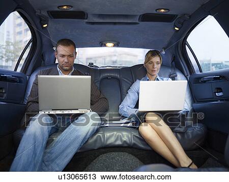 Stock Image - Businesspeople with laptops in limousine. Fotosearch