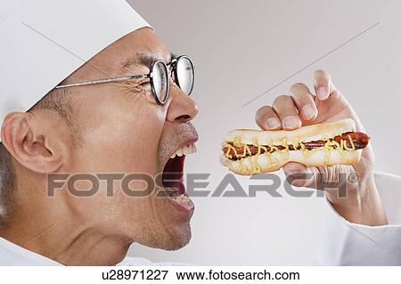 Stock Photo - Chef about to eat a hotdog. Fotosearch