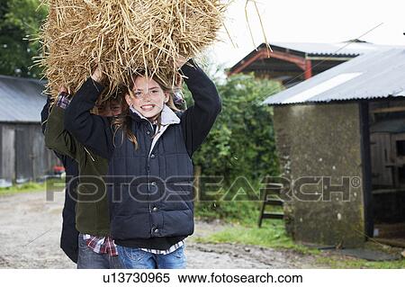 Stock Photography - Children carrying straw bale on farm. Fotosearch