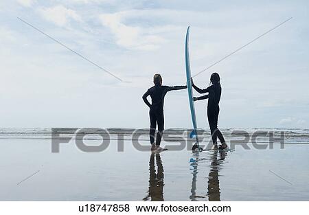 Stock Photo - Children holding surf board on beach. Fotosearch