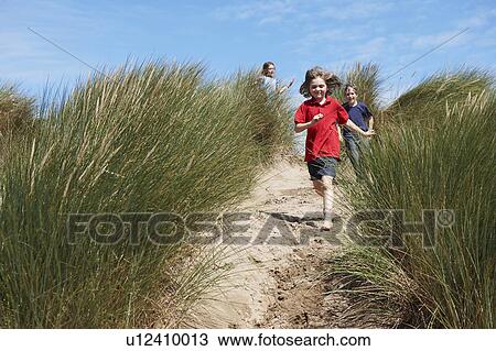 Stock Image - Children running through Sand Dunes. Fotosearch