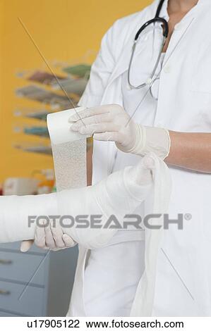 Stock Image - Close up of hands applying a dressing. Fotosearch