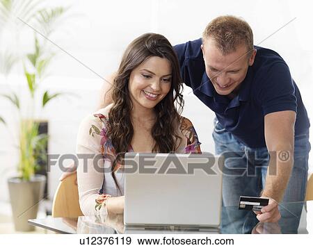 Stock Photo - Couple at home shopping online. Fotosearch