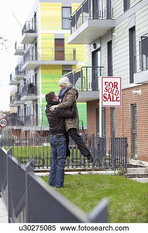 Stock Photography - Couple celebrating in front of apartment. Fotosearch