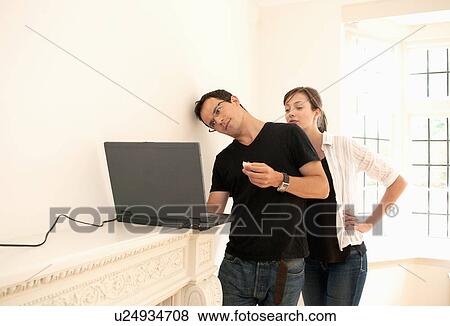 Stock Photo - Couple check emails in new home. Fotosearch