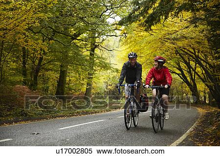 Couple cycling along country road View Large Photo Image Stock Photography - Couple cycling along country road. Fotosearch