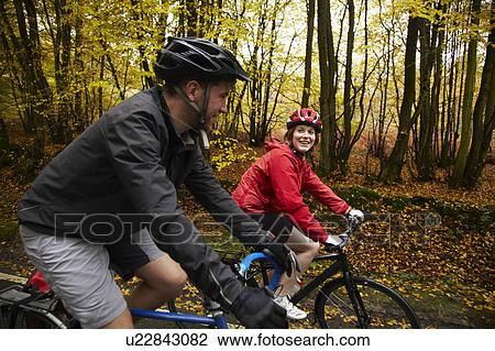 Couple cycling in the countryside View Large Photo Image Stock Image - Couple cycling in the countryside. Fotosearch
