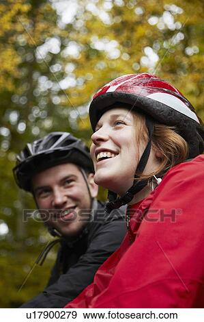 Stock Photo - Couple cycling through trees. Fotosearch
