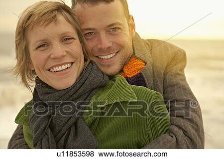 Stock Photo - Couple embracing on a beach Autumn Fall. Fotosearch