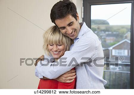 Stock Image - Couple hugging in their new apartment. Fotosearch