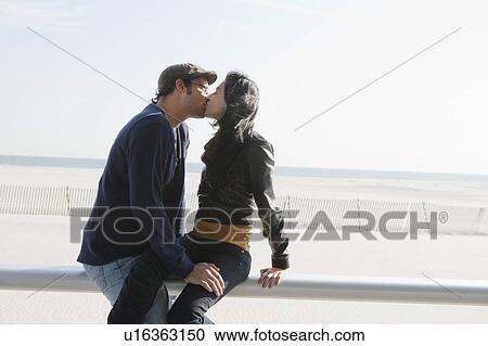 Stock Image - Couple kissing by beach. Fotosearch