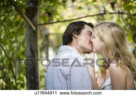 Stock Image - Couple kissing in garden. Fotosearch