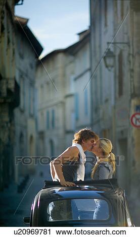 Stock Image - Couple kissing through car roof top. Fotosearch